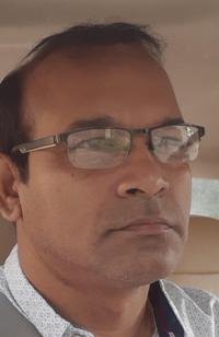 Portrait of Dr. Kapoor wearing traditional attire with academic books in background